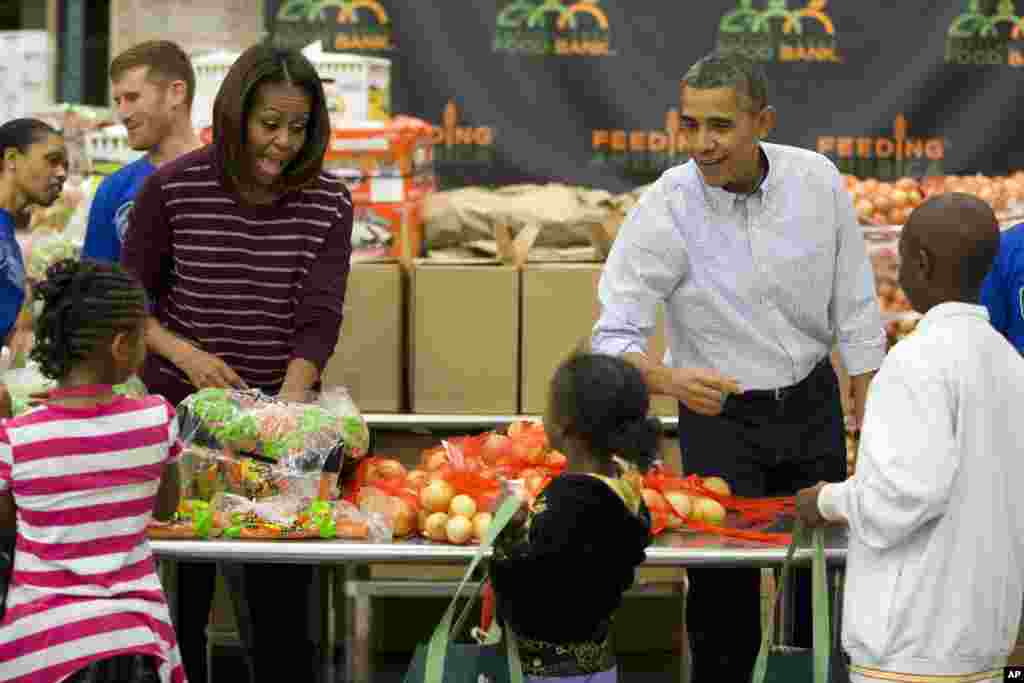 President Barack Obama, right, and first lady Michelle Obama participate in a Thanksgiving service project by handing out food at the Capital Area Food Bank in Washington, Nov. 27, 2013.