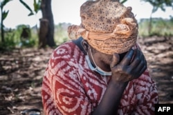 FILE - A woman in Lukodi town, Uganda, where dozens were killed in 2004 by the Lord's Resistance Army, weeps as she listens to Dominic Ongwen's verdict on the radio, Feb. 4, 2021. ICC convicted the Lord's Resistance Army commander of war crimes and crimes against humanity.