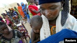Seorang perempuan menggendong bayinya, yang mengenakan gelang merah yang menunjukkan bahwa dia kekurangan gizi parah, di desa Darbani di Niger barat laut (foto: dok).