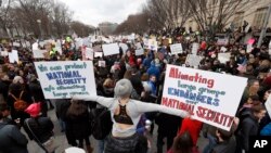 Protesters carry signs and chant on Pennsylvania Avenue near the White House during a demonstration to denounce President Donald Trump's executive order that bars citizens of seven predominantly Muslim-majority countries from entering the U.S. on Sunday, 
