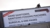 FILE - A worker attaches a billboard, advertising sales of hand sanitizer and masks, to a building ahead of a 21 day lockdown aimed at limiting the spread of coronavirus disease (COVID-19), in Cape Town, South Africa, March 25, 2020. 