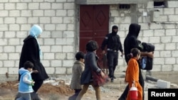 People from the northern Syrian town of Ras al-Ain attempt to cross into Turkey, as a Free Syrian Army fighter leaves a home in the background, as seen from the Turkish border town of Ceylanpinar, Sanliurfa province, November 13, 2012.