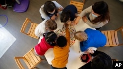 FILE- Children play with a therapist in the pediatric unit of the Robert Debre hospital, in Paris, France, March 2, 2021. 