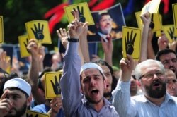 FILE - Pro-Islamist demonstrators shout slogans in favor of former Egyptian President Mohamed Morsi and hold signs that show the Rabaa hand gesture, which symbolizes support for the Muslim Brotherhood, during a rally Istanbul, Turkey, May 24, 2015.