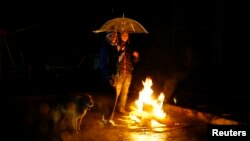 People gather around a bonfire during a blackout after an earthquake hit Chile's central zone, in Santiago, Aug. 23, 2014.