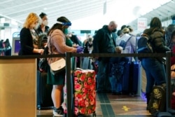 FILE - Travelers wear face masks while waiting to check in at the Southwest Airlines counter in Denver International Airport, Dec. 22, 2020, in Denver.