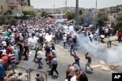 Palestinians run from tear gas thrown by Israeli police officers outside Jerusalem's Old City, July 21, 2017.