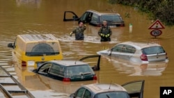 Helpers check for victims in flooded cars on a road in Erftstadt, Germany, July 17, 2021. 