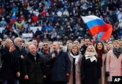 Russian President Vladimir Putin, center, and other guests sing Russia's national anthem during a massive rally in his support as a presidential candidate at the Luzhniki stadium in Moscow, March 3, 2018.