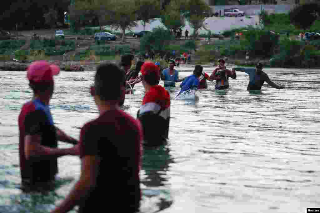Asylum seekers wait on the banks of the Rio Bravo river after crossing during their journey through Mexico to Eagle Pass, Texas, in Piedras Negras, Mexico, Sept. 26, 2023.