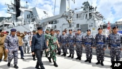 FILE - In this Jan. 8, 2020, file photo released by Indonesian Presidential Office, Indonesian President Joko Widodo, center, inspects troops during his visit at Indonesian Navy ship KRI Usman Harun at Selat Lampa Port, Natuna Islands, Indonesia.