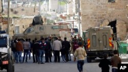 Israeli security forces stand guard as Jewish settlers are forced out of two homes in the West Bank city of Hebron, Jan. 22, 2016.