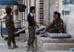 Turkey-backed Syrian rebel fighters chat in the border town of Tal Abyad, Syria, Oct. 18, 2019.