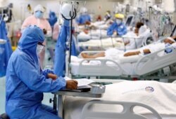 FILE - A medical worker takes notes near a patient at the intensive care unit (ICU) of the Emergencias de Villa El Salvador hospital, during the outbreak of the coronavirus disease (COVID-19), in Lima, Peru, Dec. 22, 2020.