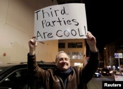 Libertarian Jeff Jared of Kirkland, Wash.,holds a sign in support of third parties before former Starbucks CEO Howard Schultz speaks during his book tour in Seattle, Jan. 31, 2019.