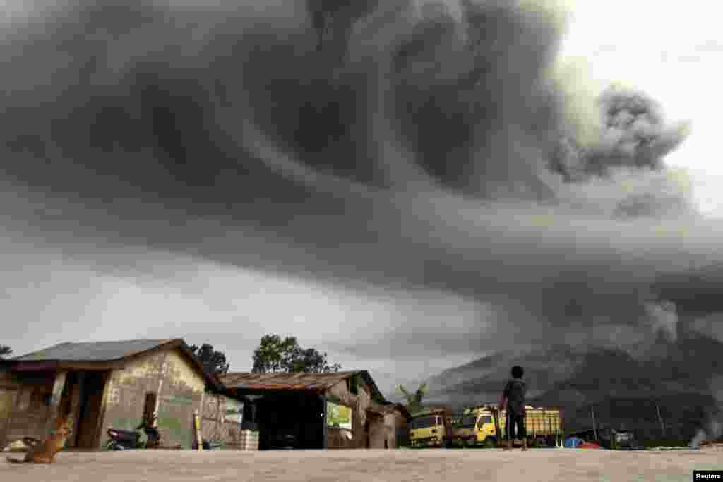 A woman looks on as Mount Sinabung spews ash, as pictured from Sibintun village in Karo district, Indonesia, Nov. 18, 2013.