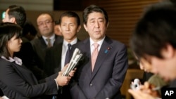 Japan's Prime Minister Shinzo Abe, center, speaks to reporters at the prime minister's official residence in Tokyo, Wednesday, Jan. 21, 2015.