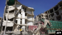 A member of the Syrian Civil Defense, also known as the White Helmets, stands in front of a heavily damaged building following an airstrike by regime forces in the rebel-held city of Idlib in northwestern Syria, July 12, 2019.