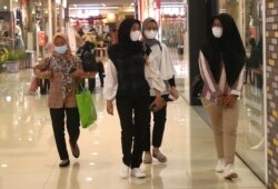 Perempuan mengenakan masker sebagai pencegahan penyebaran virus corona berjalan di sebuah pusat perbelanjaan di Tangerang, Senin, 1 Maret 2021. (Foto: AP/Tatan Syuflana)