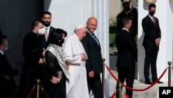 Pope Francis, center, walks with Iraqi President Barham Salih towards his plane upon concluding his visit to Iraq at the Baghdad airport, Iraq, March 8, 2021.