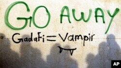 Demonstrators gather next to anti-Gaddafi graffiti in the main square of Tobruk after Gaddafi's forces seized a strategic town in eastern Libya, March 15, 2011