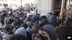 People queueing push to enter the Niketown shop in London, June 15, 2020, as after three months of being closed under coronavirus restrictions, shops selling fashion, toys and other non-essential goods are being allowed to reopen across England.