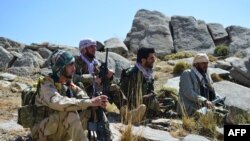 FILE - Afghan resistance movement and anti-Taliban uprising forces rest as they patrol on a hilltop in Darband area in Anaba district, Panjshir province, Sept. 1, 2021. 