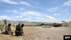 FILE - A Syrian rebel, left, takes a selfie as fellow fighters fire a missile in Aleppo province, May 9, 2019. Syrian insurgents shelled a government-held rural area in the province Sunday, reportedly killing 12 civilians.