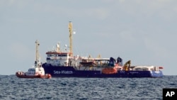 An Italian Coast Guard patrol boat flanks the Sea-Watch rescue ship off the Sicilian coast where it found shelter, about one nautical mile from Siracusa, from gale winds sweeping the Sicilian Channel, Jan. 25, 2019. 