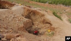 A women rock-crusher, center, works inside a rock pit in Maroua, Cameroon, June 16, 2016.