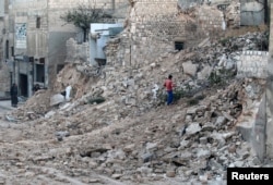 A civilian collects tree branches amid the rubble of a damaged site in the rebel-held besieged Qadi Askar neighborhood of Aleppo, Syria, Nov. 24, 2016.