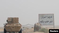 FILE - A road sign welcomes people to the town of Deir el-Zour in Syria, Sept. 20, 2017.