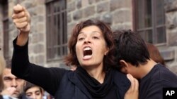 Emel Kitapci, the wife of Ali Kitapci, one of the victims from Saturday's bomb attacks, reacts as she stands with her son Artun Siyah Kitapci, 11, during a demonstration at the site of the explosions, in Ankara, Turkey, Oct. 12, 2015. 