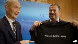 Pascal Lamy, left, Director-General of the World Trade Organization (WTO) hands over a t-shirt with a logo saying ' Welcome to the WTO...finally!' to Maxim Medvedkov, the Chief WTO negotiator for the Russian Federation in Geneva, Switzerland, November 10,