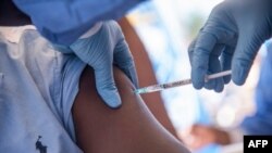 Nurses working with the WHO (World Health Organization) administer the Ebola vaccine to a local doctor in Mbandaka on May 21, 2018, during the launch of the Ebola vaccination campaign. 