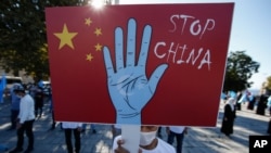 Seorang pengunjuk rasa dari komunitas Uighur yang tinggal di Turki, memegang plakat anti-China saat melakukan protes, 1 Oktober 2020. (Foto: AP)