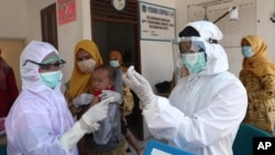 Trabajadores de salud preparan una vacuna contra el sarampión para aplicarla a un niño en Indonesia. [Foto de archivo]