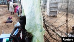 A South Sudanese woman displaced by the fighting uses her phone as she leans against a barbed wire in a camp for displaced persons in the UNMISS compound in Juba, February 19, 2014. 