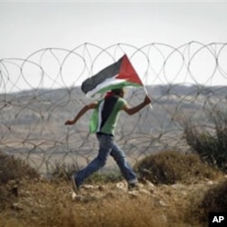 A protester carries a Palestinian flag along Israel's separation barrier near the West Bank city of Ramallah, July 9, 2011