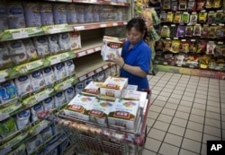 FILE - A worker removes boxes of Yili infant milk powder from a Beijing supermarket’s shelves during a product safety recall in June 2012.