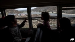 FILE - Central American children who are traveling with a caravan of migrants, look at the border wall from a bus carrying the group to a gathering of migrants living on both sides of the border, in Tijuana, Mexico, April 29, 2018. U.S. 