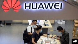 Visitors wearing masks to curb the spread of the coronavirus look at the latest products at a Huawei store in Beijing on Wednesday, July 15, 2020. (AP Photo/Ng Han Guan)