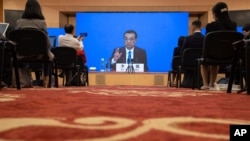 FILE - Chinese Premier Li Keqiang speaks on screen during a press conference by video conferencing at the end of the National People's Congress in Beijing, May 28, 2020. 