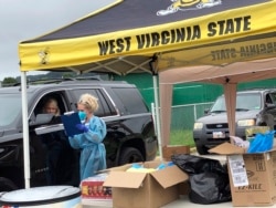 Parents and students arrive in their vehicles for health screenings and temperature checks before moving belongings into residence halls at West Virginia State University campus Friday, July 31, 2020, in Institute, W. Va. (AP Photo/John Raby)