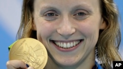 United States' Katie Ledecky shows off her gold medal in the women's 800-meter freestyle medals ceremony during the swimming competitions at the 2016 Summer Olympics, in Rio de Janeiro, Brazil, Aug. 12, 2016. 