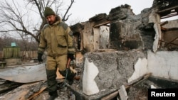 A member of a rebel unit of the self-proclaimed separatist Donetsk people's republic walks past a house destroyed by shelling in the village of Olenivka, south of Donetsk, Feb. 7, 2015.