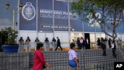 ARCHIVO - Los peatones pasan frente a la fiscalía donde la presidenta peruana Dina Boluarte llegó para testificar, en Lima, Perú, el viernes 5 de abril de 2024.