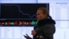 A woman walks past an information screen inside the office of the Moscow Exchange on March 14, 2014. Russian stock indexes have plunged in recent months.