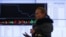 A woman walks past an information screen inside the office of the Moscow Exchange on March 14, 2014. Russian stock indexes have plunged in recent months.