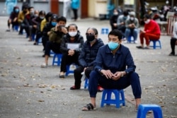 A delivery man waits for online order outside a cafe in Hanoi, Vietnam, April 1, 2020.